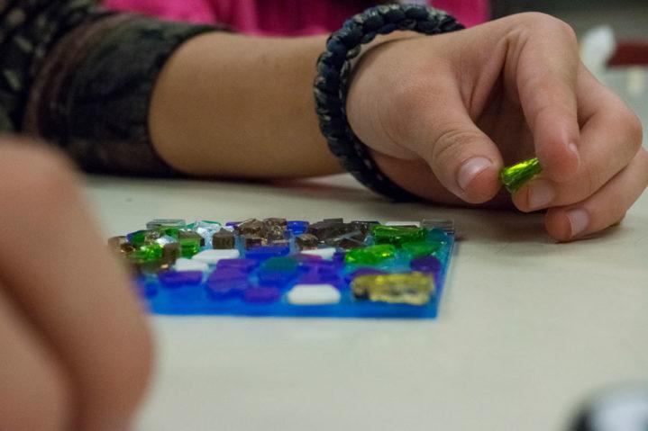 Centerville High School student close up of hand placing Gems or Jewels on art piece